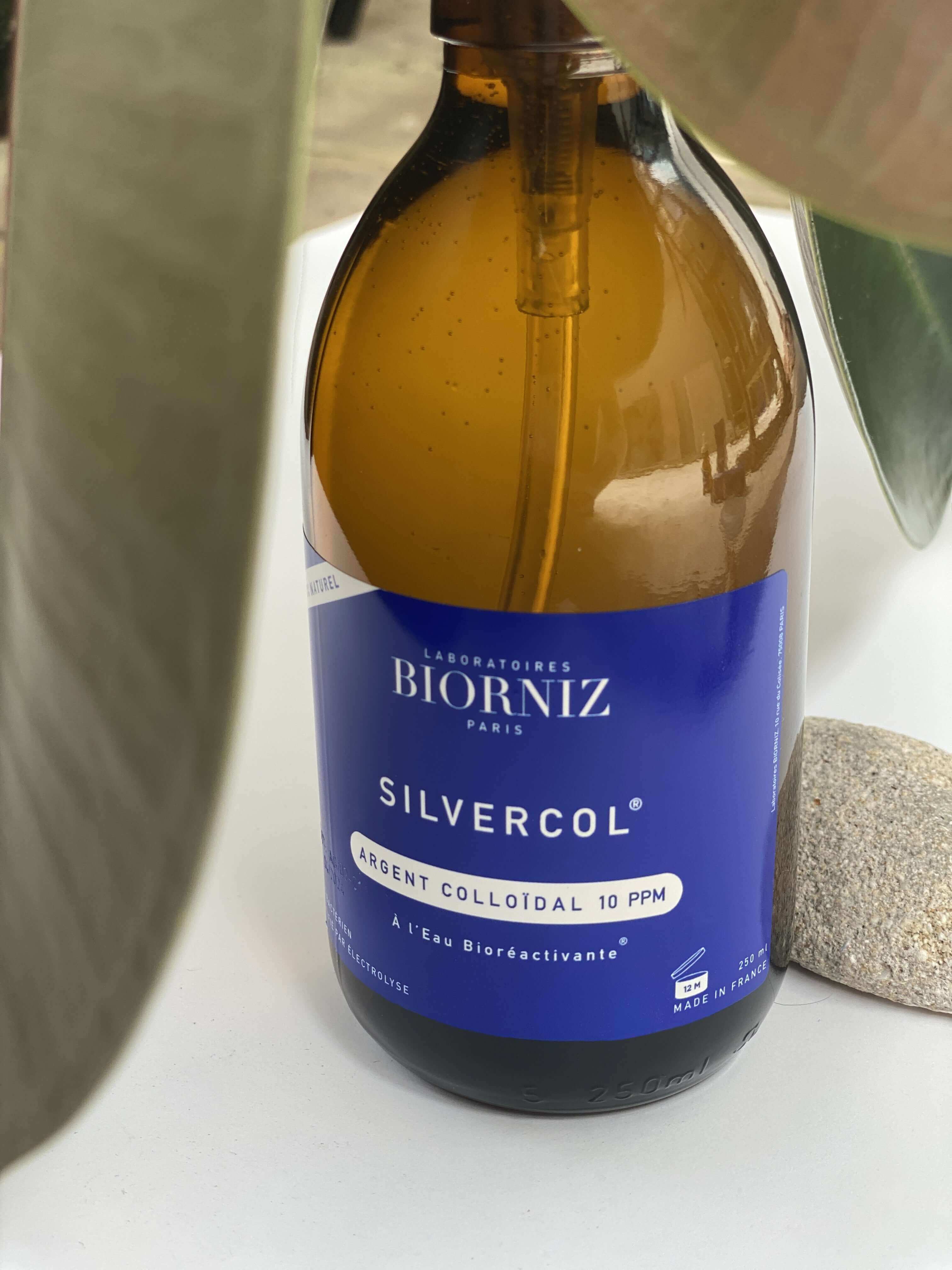 Spray 250 ml en verre d'argent colloidal 10 ppm posé au milieu de feuilles vertes